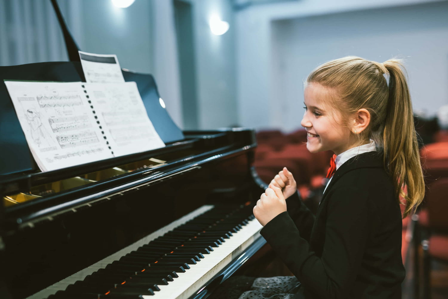 Young girl smiling after completing playing a song on the piano